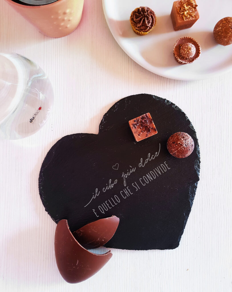 Tagliere in ardesia a forma di cuore con cioccolatini condivisi sul tavolo