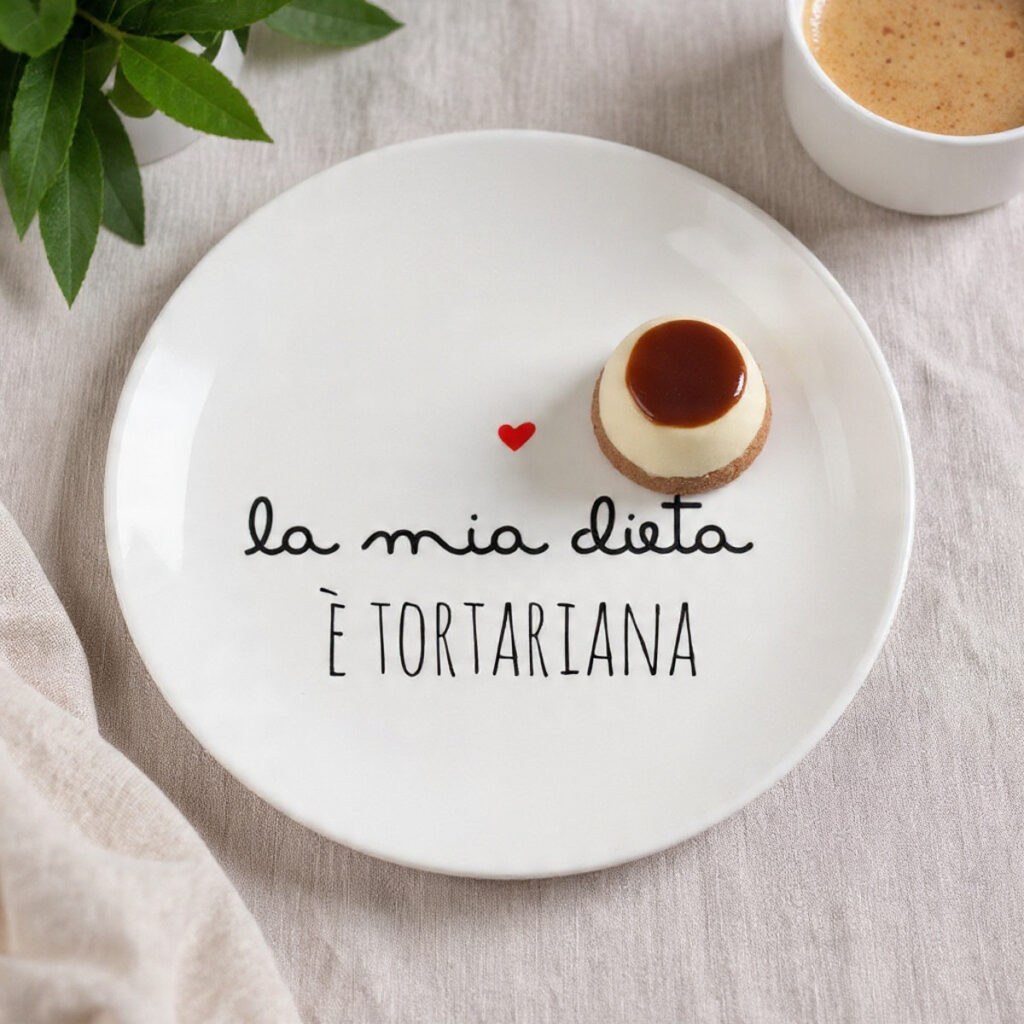 Piatto dessert bianco con scritta “la mia dieta è tortariana” e dolce al cucchiaio servito in modo minimal su tavola luminosa
